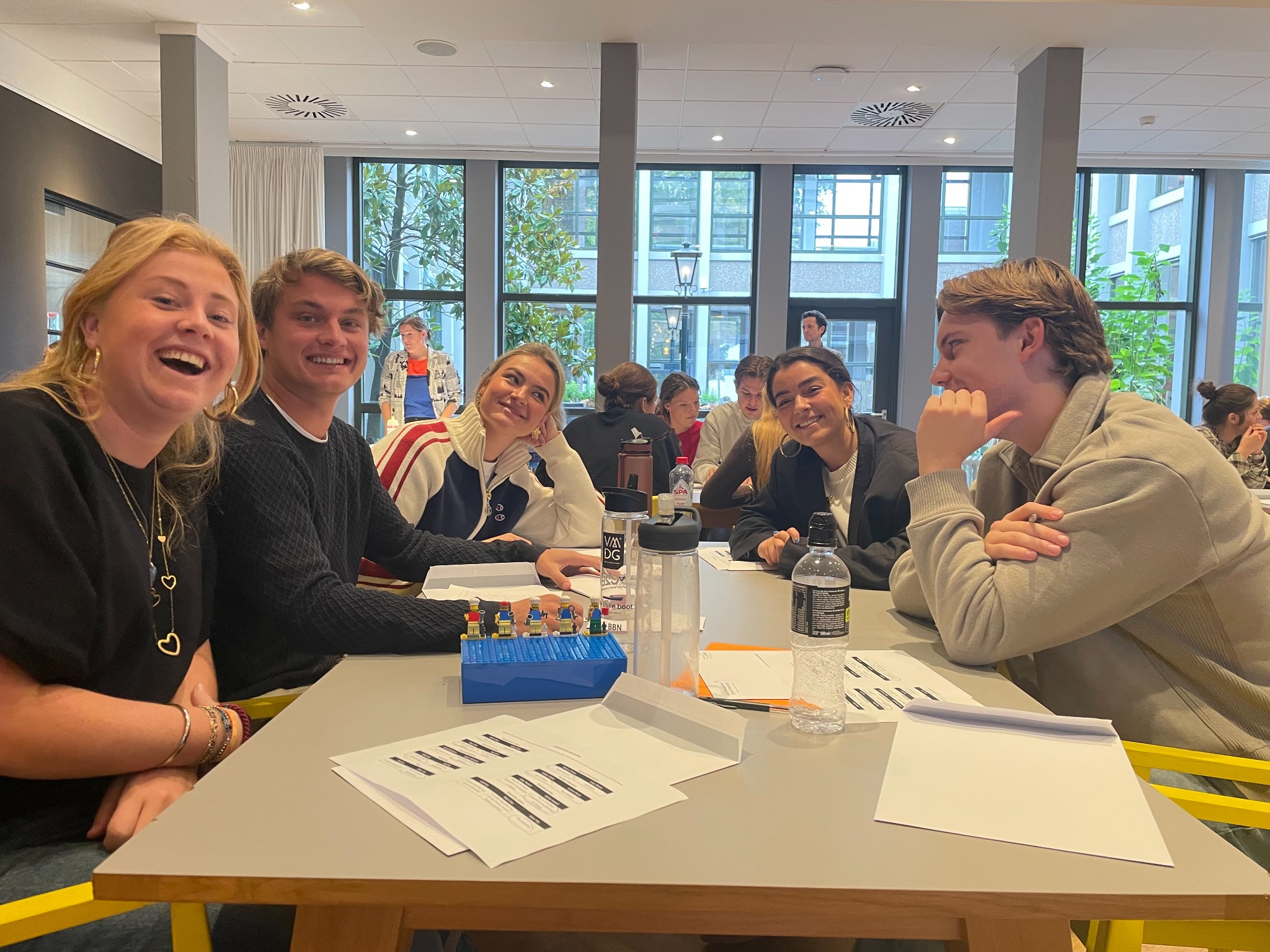 A Maastricht workshop group smiling around a table with LEGO minifigures and handouts.